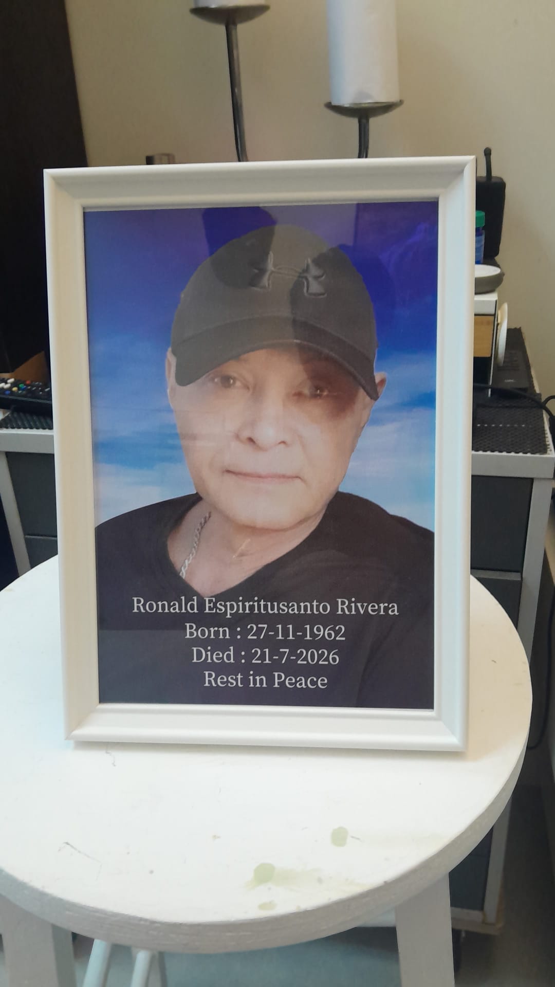 Framed memorial portrait of Ronald Espiritusanto Rivera wearing a black cap